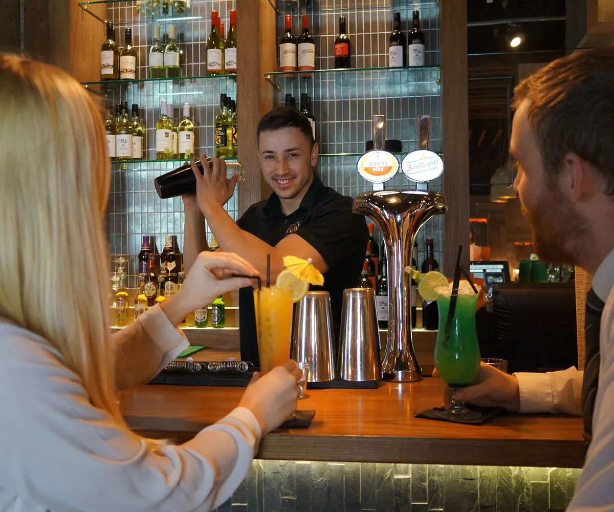 Guests being served at the bar in a Coal Grill + Bar restaurant